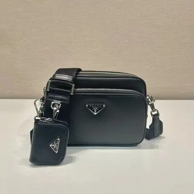 A black leather camera bag with a detachable pouch on a neutral surface