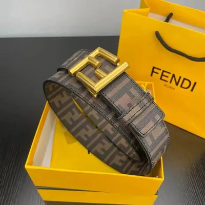 A monogram-canvas belt coiled around a large gold buckle, resting on its gift box and paper bag