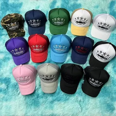 Mesh-back trucker caps in many colours laid out on a textured turquoise surface